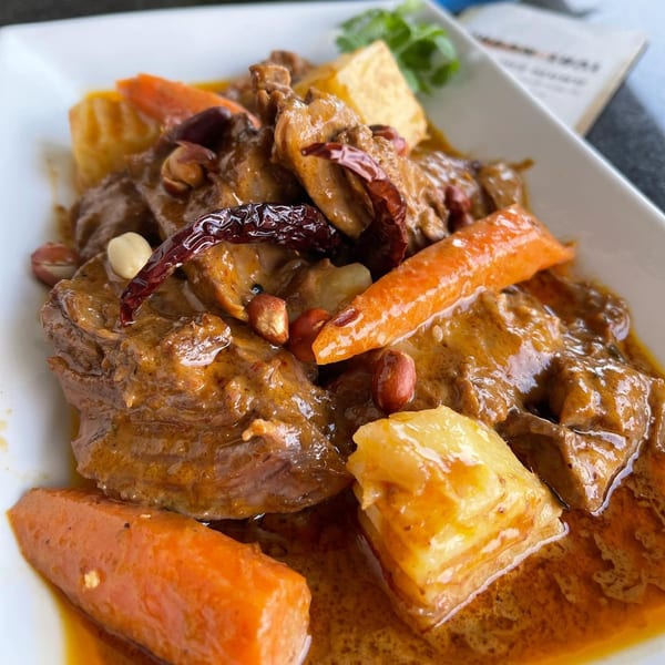 Close-up of Urban Thai Kitchen's Massaman Curry with beef, potatoes, carrots, peanuts, and dried chilies.